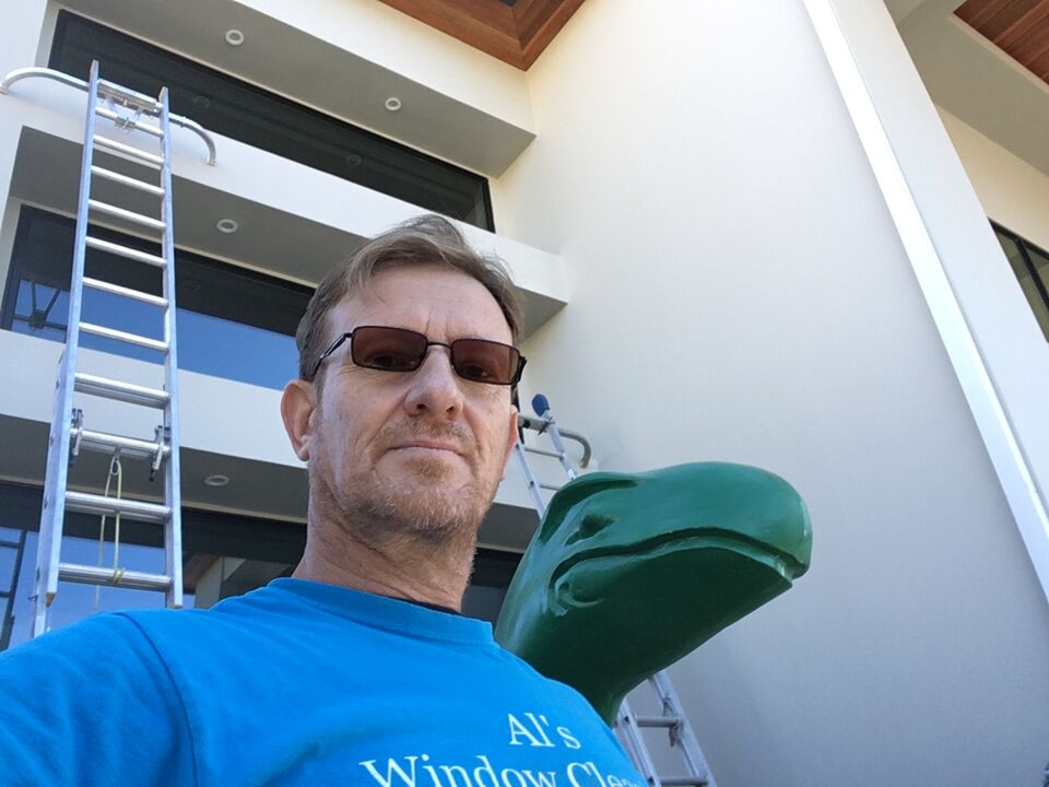 Al in a blue Al’s Window Cleaning shirt with a ladder against a modern building